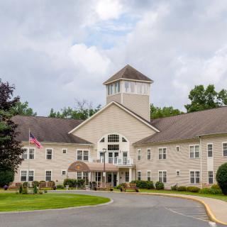 A large residential building with a prominent entrance and surrounding greenery.