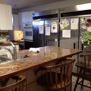 A spacious kitchen with multiple refrigerators and a central island with bar stools.