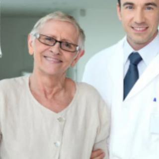 An elderly woman smiling with a doctor in a healthcare setting.
