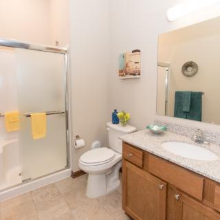 A clean bathroom with a shower, sink, and wooden cabinet.