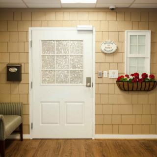A cozy waiting room with a white door, decorative flowers, and comfortable seating.