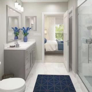 A modern bathroom with a gray vanity and blue accents, featuring a shower and decorative flowers.