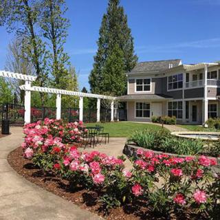 A beautifully landscaped garden with blooming flowers in front of a two-story building.
