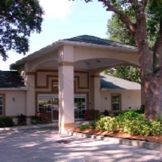 A building entrance with a covered driveway and surrounding trees.