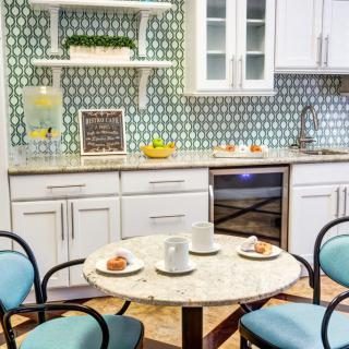 A modern kitchen with a stylish backsplash, featuring a small round table set with cups and muffins.