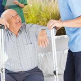 An elderly person using a walker receives assistance from a caregiver.