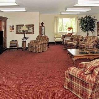 A cozy living room with plaid upholstered furniture and a red carpet.