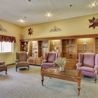 A cozy living room with comfortable chairs, wooden shelves, and elegant decor.