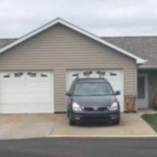 A car parked in front of a garage in a suburban neighborhood.