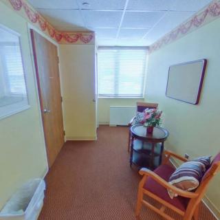 A well-lit waiting area with comfortable chairs and a small table by the window.