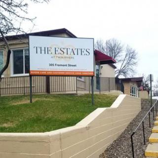 A real estate sign outside a building, advertising 'The Estates' housing complex.