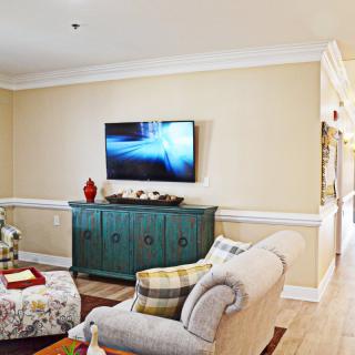 A cozy living room with a sofa, a wall-mounted television, and a teal cabinet.