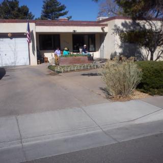 A suburban house with a front porch, driveway, and surrounding yard.