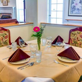 A neatly set dining table with folded napkins and a flower centerpiece in a cozy restaurant setting.