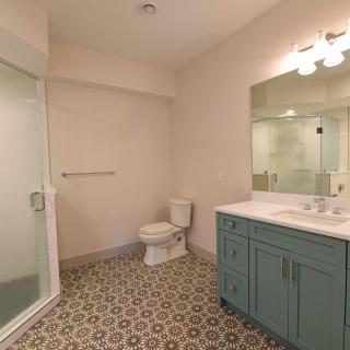 A modern bathroom with a glass shower, toilet, and a vanity with a large mirror.