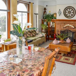 A cozy living room with a table, sofa, and fireplace surrounded by plants and decor.