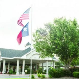 A building entrance with American and Texas flags flying overhead.