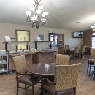 A cozy dining area with a chandelier and neatly arranged tables and chairs.