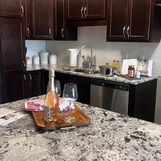 A kitchen with a granite countertop featuring a wine bottle and glasses on a tray.