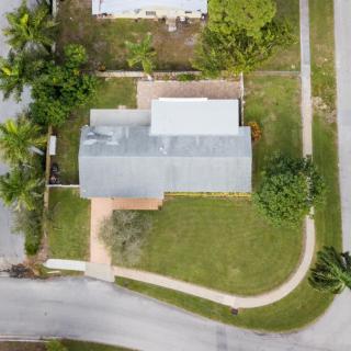 Aerial view of a residential house with a well-maintained lawn and surrounding roads.