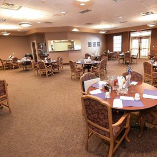 A cozy dining area with neatly arranged tables and chairs, well-lit for a welcoming atmosphere.