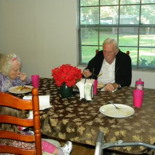 An elderly couple having a meal together at a dining table.