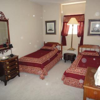 A traditionally decorated bedroom with twin beds and matching red bedspreads.