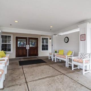 A covered building entrance with decorative benches and colorful cushions.