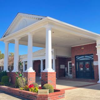 A welcoming entrance with classic columns and vibrant landscaping under a clear blue sky.