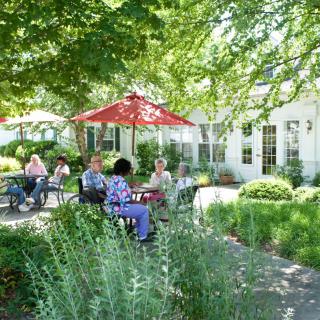 People sitting and relaxing in a garden patio under red umbrellas.