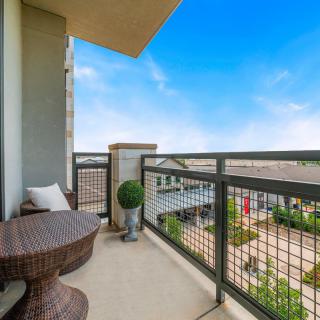 A cozy balcony with wicker furniture, offering a pleasant view under a clear blue sky.