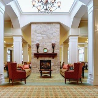 A luxurious living room with a central fireplace, elegant chandelier, and comfortable seating.