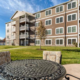 A modern apartment building with a well-maintained lawn and outdoor seating.