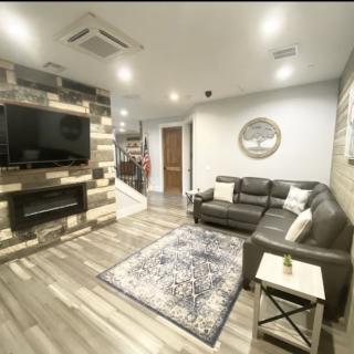 A cozy modern living room with a large sofa, wall-mounted television, and wooden floors.