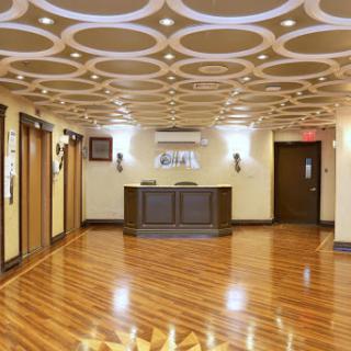 A spacious and elegantly designed hotel lobby with stylish ceiling patterns and a warm wooden floor.