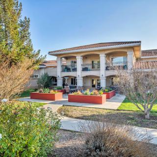 A beautiful residential building featuring balconies and landscaped gardens under a clear blue sky.