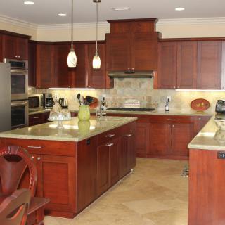 A modern kitchen with wooden cabinets, a central island, and elegant pendant lighting.