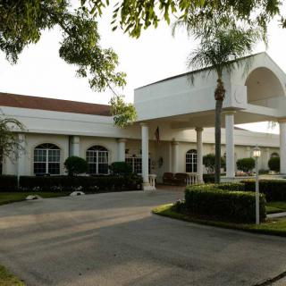 A large building with landscaped gardens and a palm tree, possibly a hotel or resort entrance.