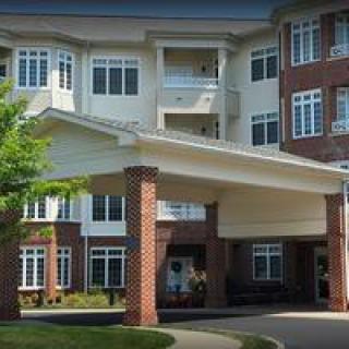 A view of a residential building with a covered entrance and numerous windows.