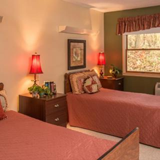 A cozy bedroom featuring twin beds with warm lighting and a window view.