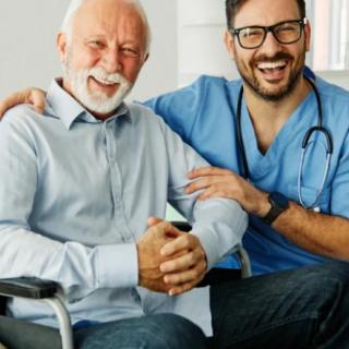 A smiling doctor with an elderly patient in a wheelchair.