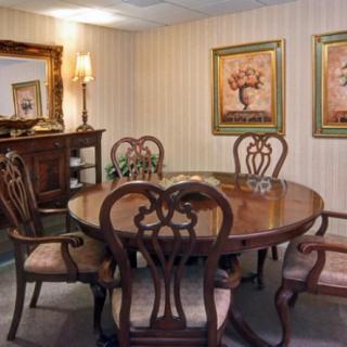 A traditional dining room with a wooden table and chairs, adorned with wall art and a decorative sideboard.