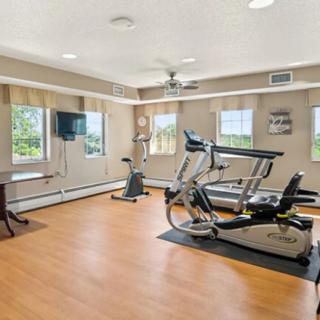 A well-lit exercise room with fitness equipment, including a treadmill and stationary bike.