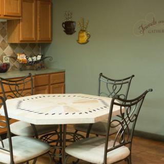 A cozy kitchen dining area with a round table and decorative wall art.