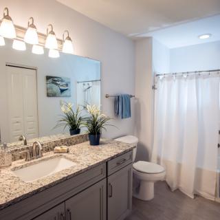 A modern bathroom with a granite countertop vanity, large mirror, and soft lighting.