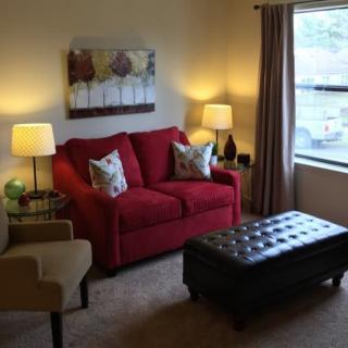 A cozy living room with a red sofa, armchair, and a large window.