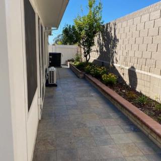 A well-maintained backyard with a paved pathway and landscaped garden along the fence.