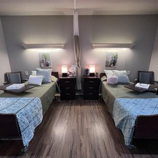 A modern bedroom featuring two neatly arranged twin beds with matching nightstands and lamps, showcasing symmetrical interior design.
