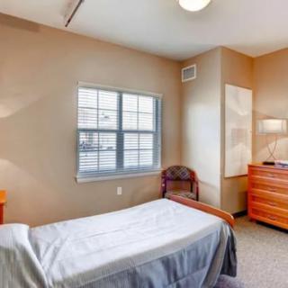 A minimalist bedroom with a single bed, dresser, and window.