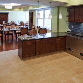A modern kitchen and dining area with wooden cabinets and elegant lighting.